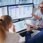 Young pensive analyst in smart casualwear looking at data on computer screen while working